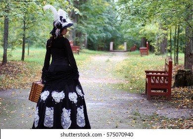 Girl In Retro Dress 18th Century With Valise In Park