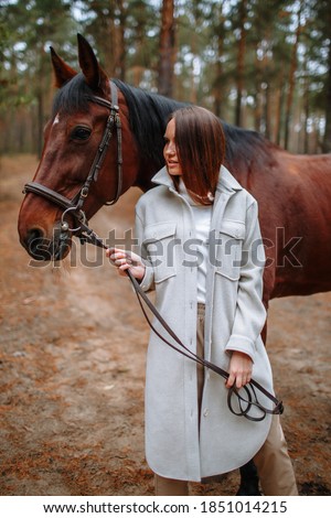 Girl rider standing next to a horse