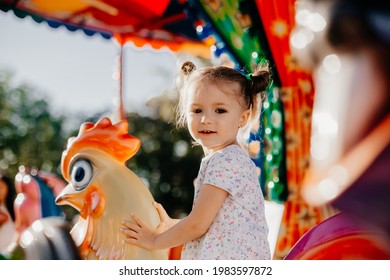 The girl rides an amusement park in the park located on the shores of a seaside resort. Happy child on vacation with family