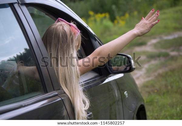 girl rides\
in the car and waving from the\
window,