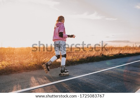 a girl rides on roller skates against the background of the sunset