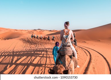 Girl Riding A Camel In Sahara Desert Morocco. Camel Expedition In The Desert.