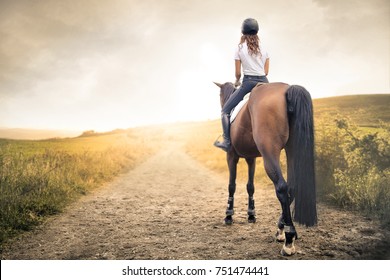 Girl riding her horse in a path in the hills