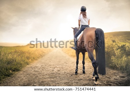 Girl riding her horse in a path in the hills