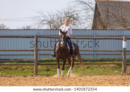 Girl riding a horse gallops in a paddock on a ranch