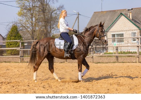 Girl riding a horse gallops in a paddock on a ranch