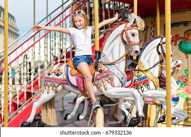 Girl riding on a merry go round. Little girl playing on carousel, summer fun, happy childhood and vacation concept