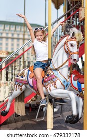 Girl Riding On A Merry Go Round. Little Girl Playing On Carousel, Summer Fun, Happy Childhood And Vacation Concept