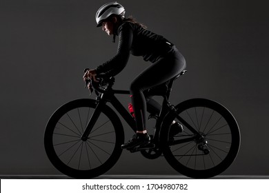 Girl Riding Road Bike. Studio Shot Against Dark Background.