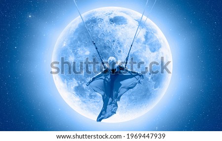The girl riding a swing on the space on a full moon at night 