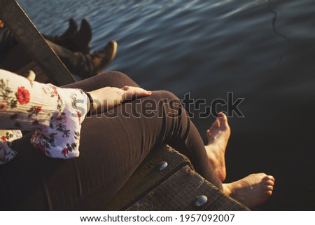 Girl with ring sitting on edge of pier above water