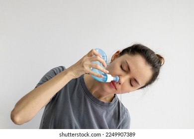 Girl rinses her nose with saline solution at home Using Neti Pot. Treatment and prevention of colds. How to rinse your nose when you have a runny nose.