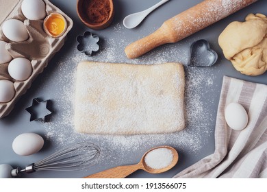 The girl rolls out the dough with a wooden rolling pin for making cupcakes or cookies. Flat composition with kitchen utensils and ingredients, copy space. Concept of baking for the holiday. - Powered by Shutterstock