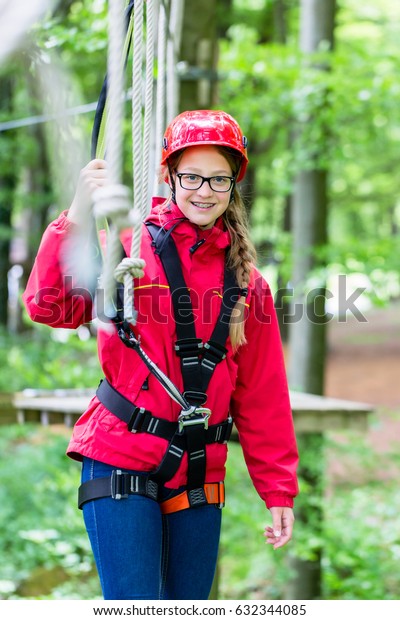 Girl roping up in high rope course exercising\
the necessary safety\
precautions