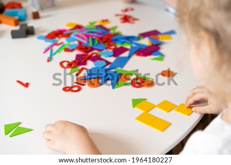 a girl at a round white table plays educational games, a house made of designer children's hands, the concept of development of preschoolers.