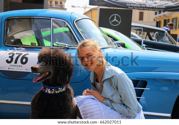 Girl\
with a royal poodle on a retro car background.Open event 1000 Miles\
Annual race of retro auto. Brescia Italy May 18\
2017