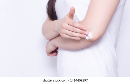 The girl rubs the healing cream and balm in the elbow joint to relieve pain and inflammation, white background, copy space, anti-inflammatory - Shutterstock ID 1414409297