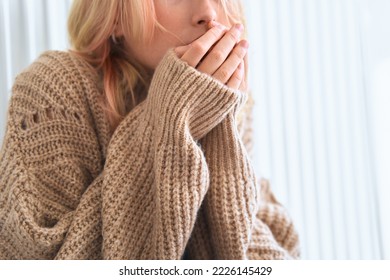 Girl rubs her hands trying to keep warm in the cold season. Cold weather. Child feels cold. Young girl puts on sweater. Comfort relaxation in cold season concept. Heating radiator is not warm. - Shutterstock ID 2226145429