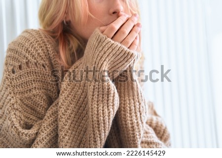 Girl rubs her hands trying to keep warm in the cold season. Cold weather. Child feels cold. Young girl puts on sweater. Comfort relaxation in cold season concept. Heating radiator is not warm.