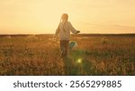 Girl run in meadow kicking ball with her foot. Cheerful child running in nature, playing football with ball. Sports lifestyle for child in nature. Active girl child. Family in park. Children football