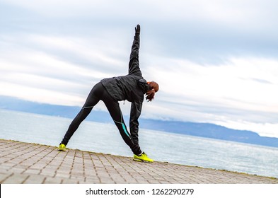 Girl Runner Warming Up And Stretching By The Lake In Cold Winter Time