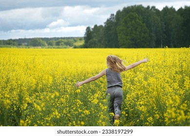 Girl running across a field with yellow flowers