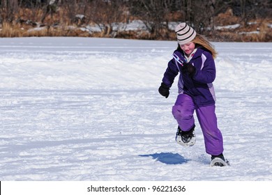 Girl Running Across Frozen Lake In Winter Snowshoe Race