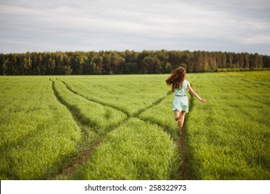 Girl Running Along A Path In A Field At Sunset