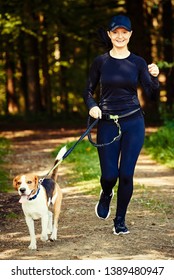 Girl running with dog outdoors in nature on a path in forest. Sunny day countryside. Copy space for text