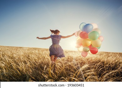 Girl running on the field with balloons at sunset. Happy woman on nature.  - Powered by Shutterstock