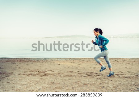 Girl running on sand beach near the sea in summer in the morning. Concept of sport and healthy lifestyle. Space for text in the left part of image