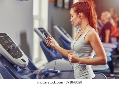 Girl Running On The Treadmill And Listening To Music At The Gym, Soft Focus Picture