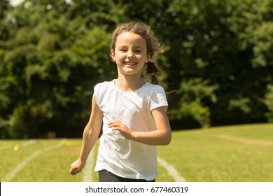 Girl Running At School Sports Day. Young Child Sprinting Hard And Happily During Summer Traditional School Event