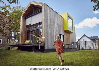 Girl running towards happy mother sitting outside tiny house