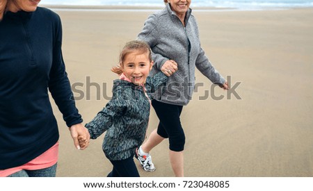 Little girl running with women on beach