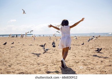 Girl Runs On The Beach Dispersing Birds Seagulls And They Fly