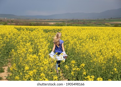 The Girl Runs On A Spring Field Of Yellow Flowers.