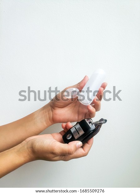 A girl Sanitizing her car keys with a bottle of hand\
sanitizing 