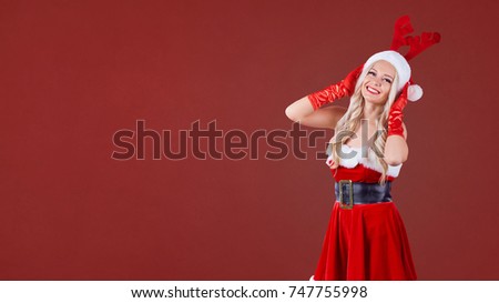 A girl in Santa's costume with deer horns.