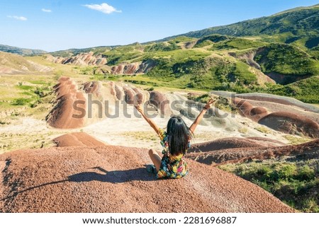Girl in a scenic nature sits and lifts hands out of joy. ravel in Georgia