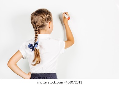 girl in a school uniform writing something on board with a marker. Learning and school concept. Image on white background.