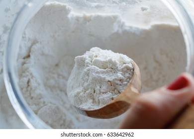The girl scoops the flour with a wooden spoon. Close-up. - Shutterstock ID 633642962