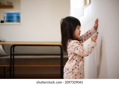 Girl scribbling on the wall 
				