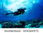 Girl scuba diver diving on tropical reef with blue background and reef fish