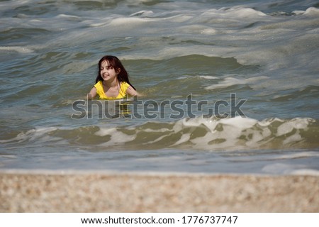 Girl at sea. The portrait of the young girl. Teenager summer vacation sand. Sunny day and the sea. Childhood travel vacation. Teenager in a yellow swimsuit on the beach. Teenager swims in the sea