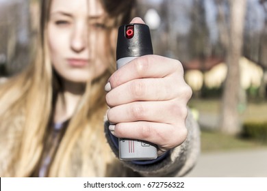 A girl with a serious face holding  Tear Gas Spray for Self Defense. Pepper spray