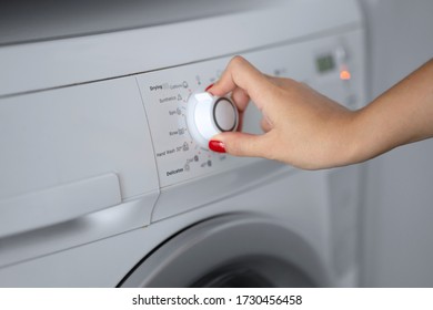 The girl sets the washing program for the washing machine