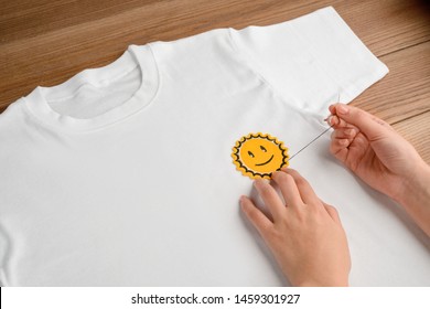 Girl Sewing An Embroidered Smiling Sun Patch On A White Blank T-shirt. Easy DIY Project To Upgrade Your Style.