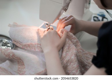 The girl sews a tweed skirt on a sewing machine, uses household equipment. Concept: atelier, cutting and sewing courses, custom tailoring, self-sewing, creative workshop. - Powered by Shutterstock