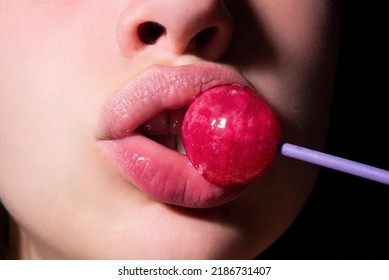 Girl with sexy mouth eating chupa chups close up. Woman lips sucking lollypop. Oral sex blow job concept. Woman holding lollipop in mouth, close up. Red lips, sensual and sex shop concept.